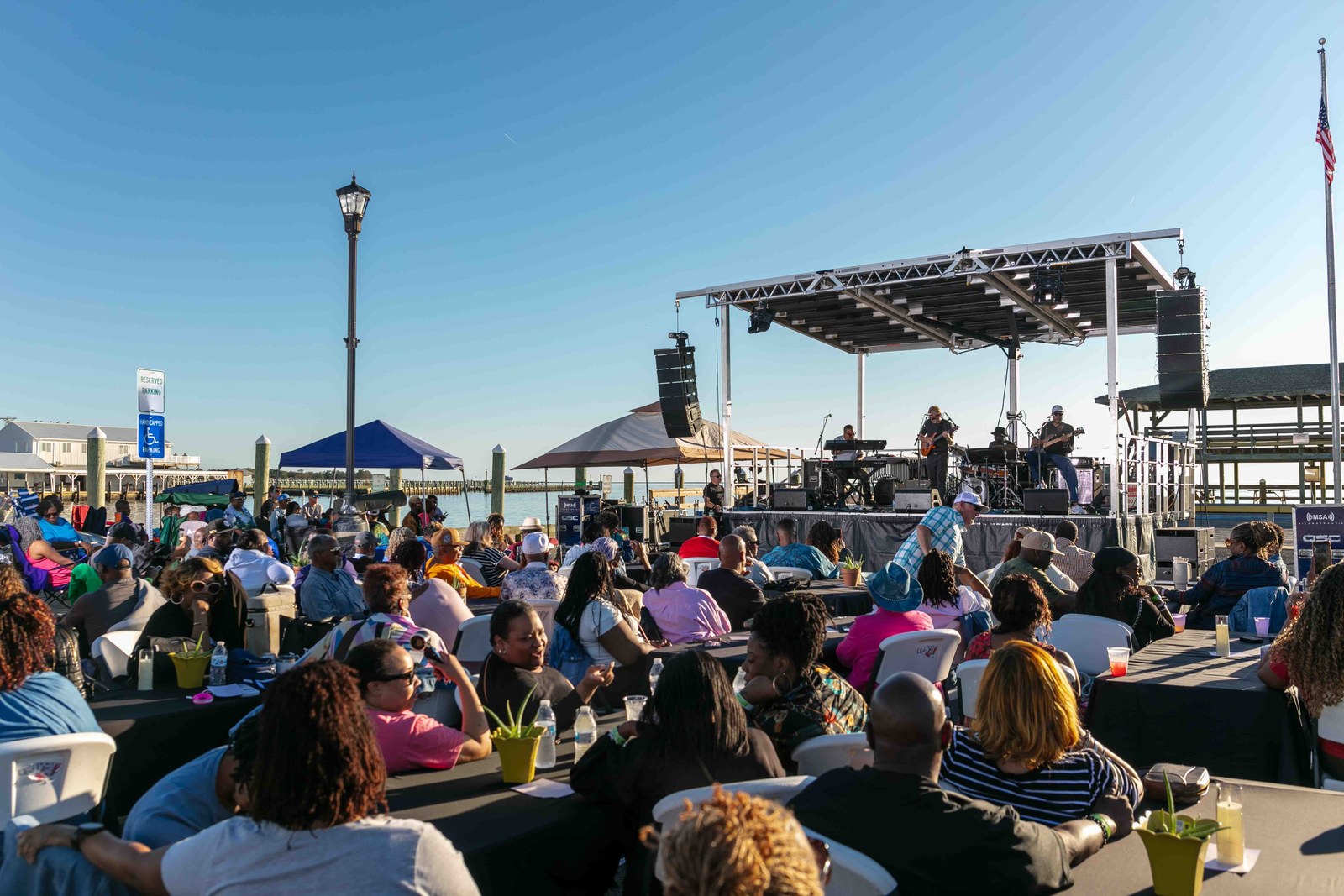 Guests enjoying live music at tables beside the water during the 2025 festival